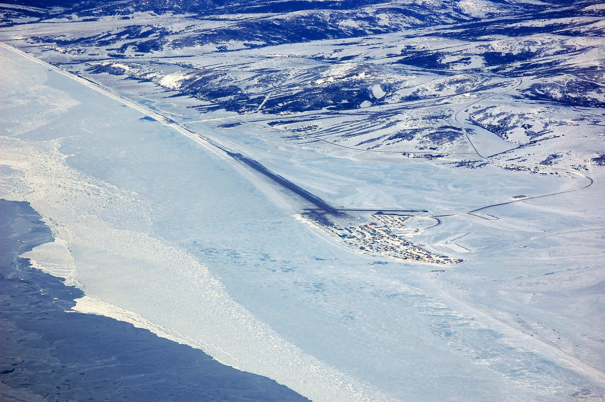Aerial view of Unalakleet village beside the frozen coast and inland hills